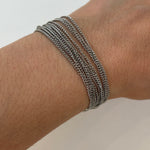 Bracelet multirangs Lyv en acier inoxydable argenté porté au poignet, style accumulation tendance.