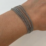 Bracelet multirangs Lyv en acier inoxydable argenté porté au poignet, style accumulation tendance.