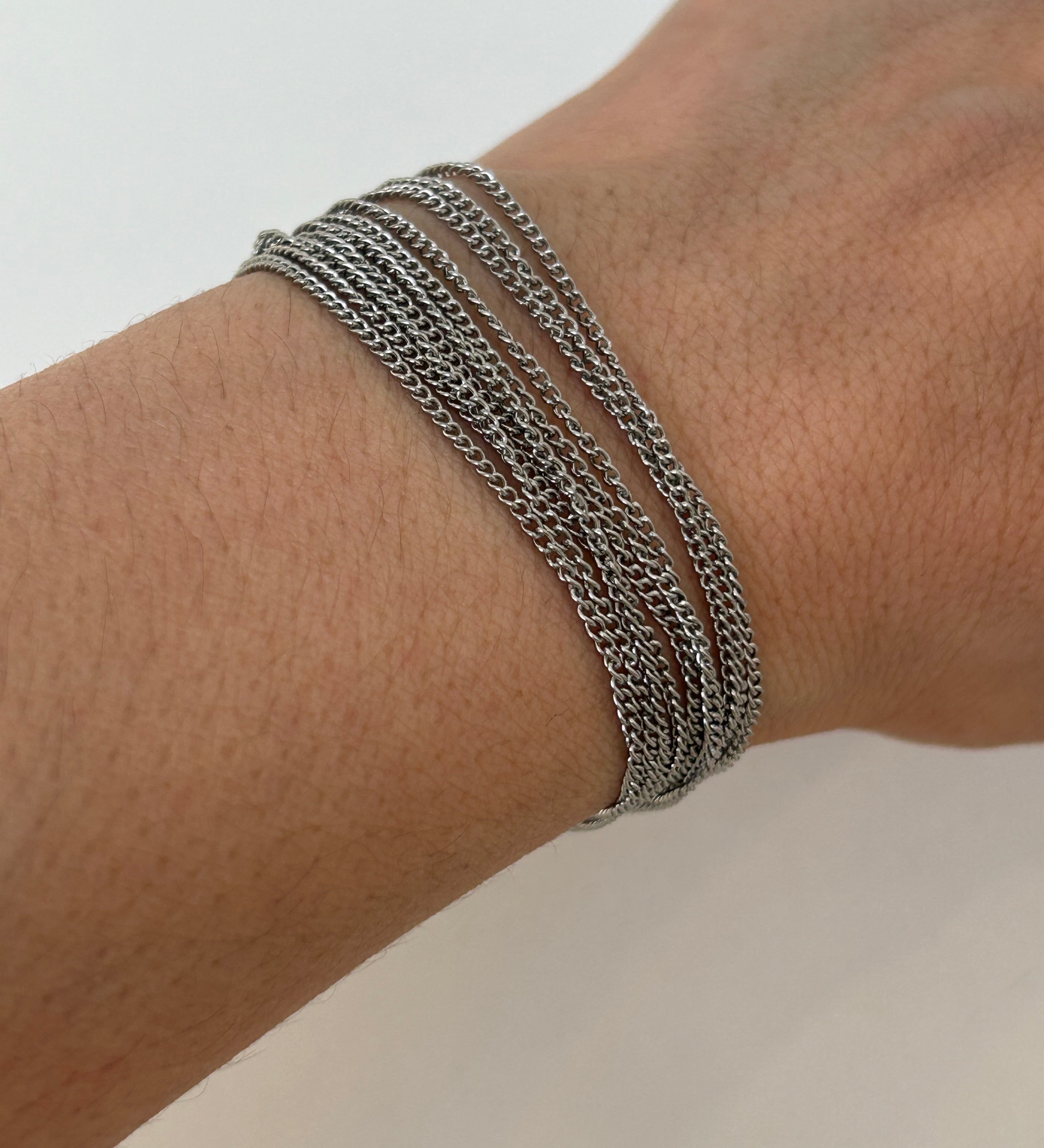 Bracelet multirangs Lyv en acier inoxydable argenté porté au poignet, style accumulation tendance.