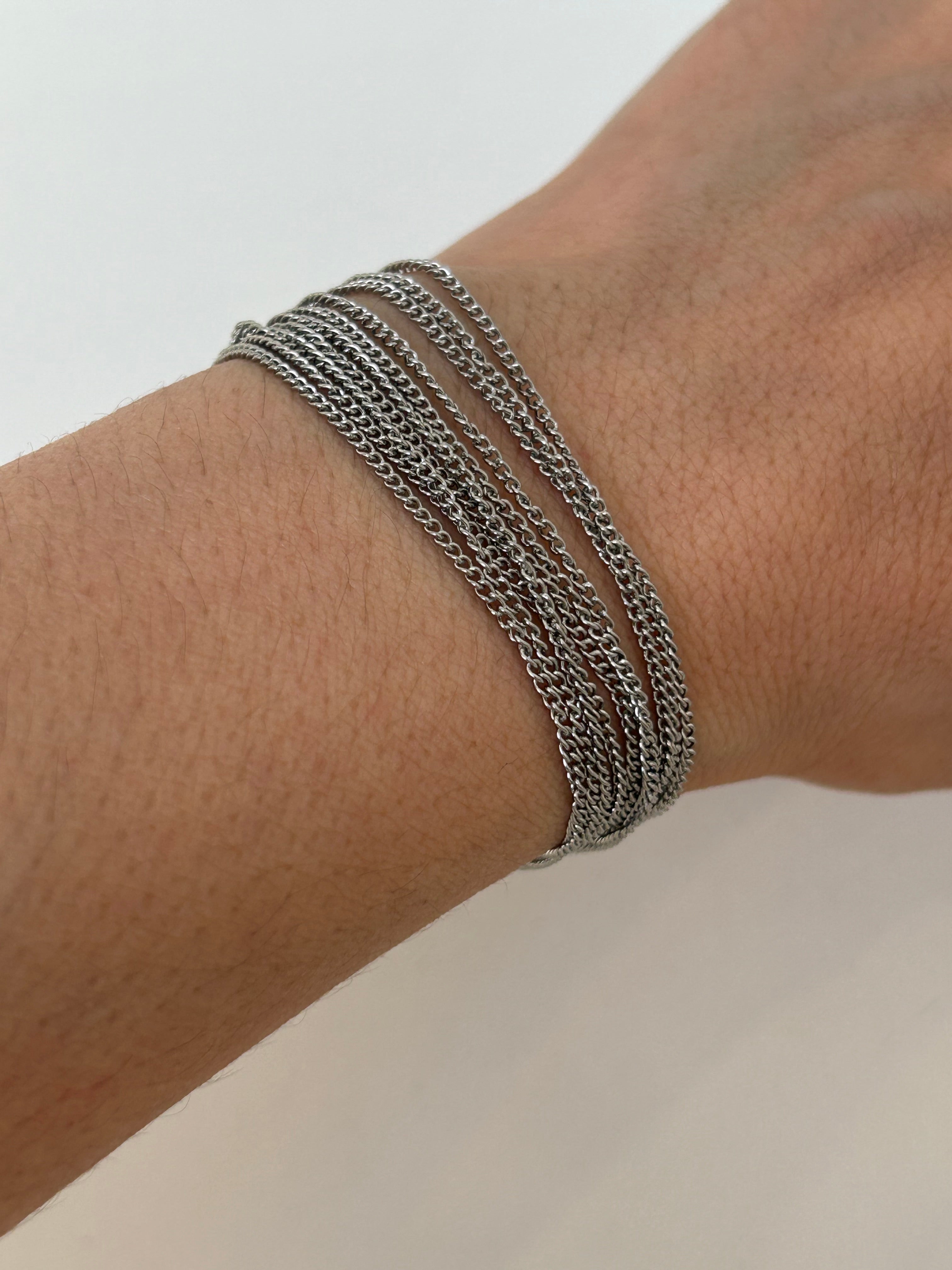 Bracelet multirangs Lyv en acier inoxydable argenté porté au poignet, style accumulation tendance.