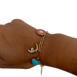 Bracelet Mystique doré avec charm cœur rouge porté au poignet.