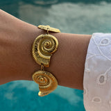 Bracelet Sora doré motif coquillage porté en extérieur au bord de l'eau - Ordiajade

