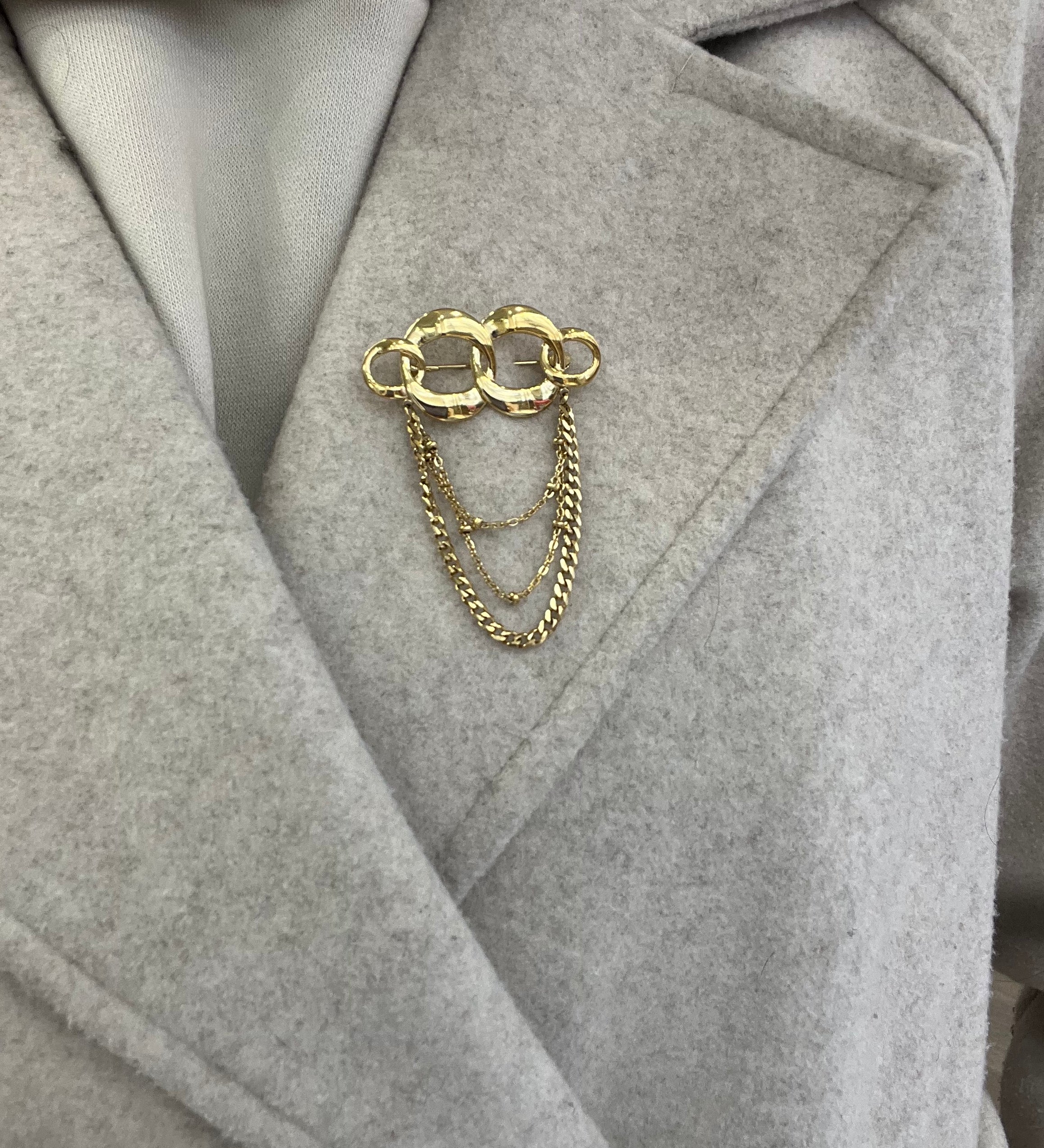 Broche Olympiade dorée en acier inoxydable maillons entrelacés avec chaînettes pendantes portée sur manteau - Ordiajade