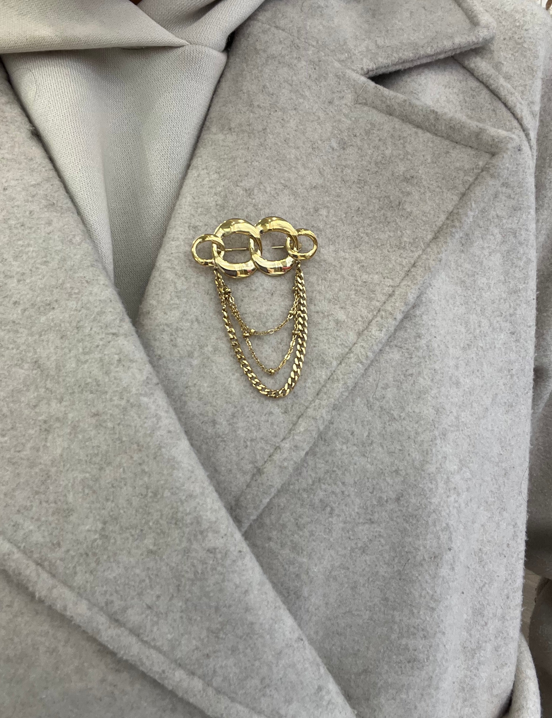 Broche Olympiade dorée en acier inoxydable maillons entrelacés avec chaînettes pendantes portée sur manteau - Ordiajade