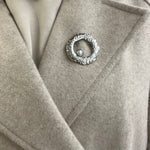 Broche Sylviane argentée en acier inoxydable anneau martelé avec perle portée sur le revers d'un manteau beige - Ordiajade