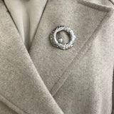 Broche Sylviane argentée en acier inoxydable anneau martelé avec perle portée sur le revers d'un manteau beige - Ordiajade