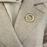 Broche Sylviane dorée en acier inoxydable anneau martelé avec perle portée sur le revers d'un manteau beige - Ordiajade