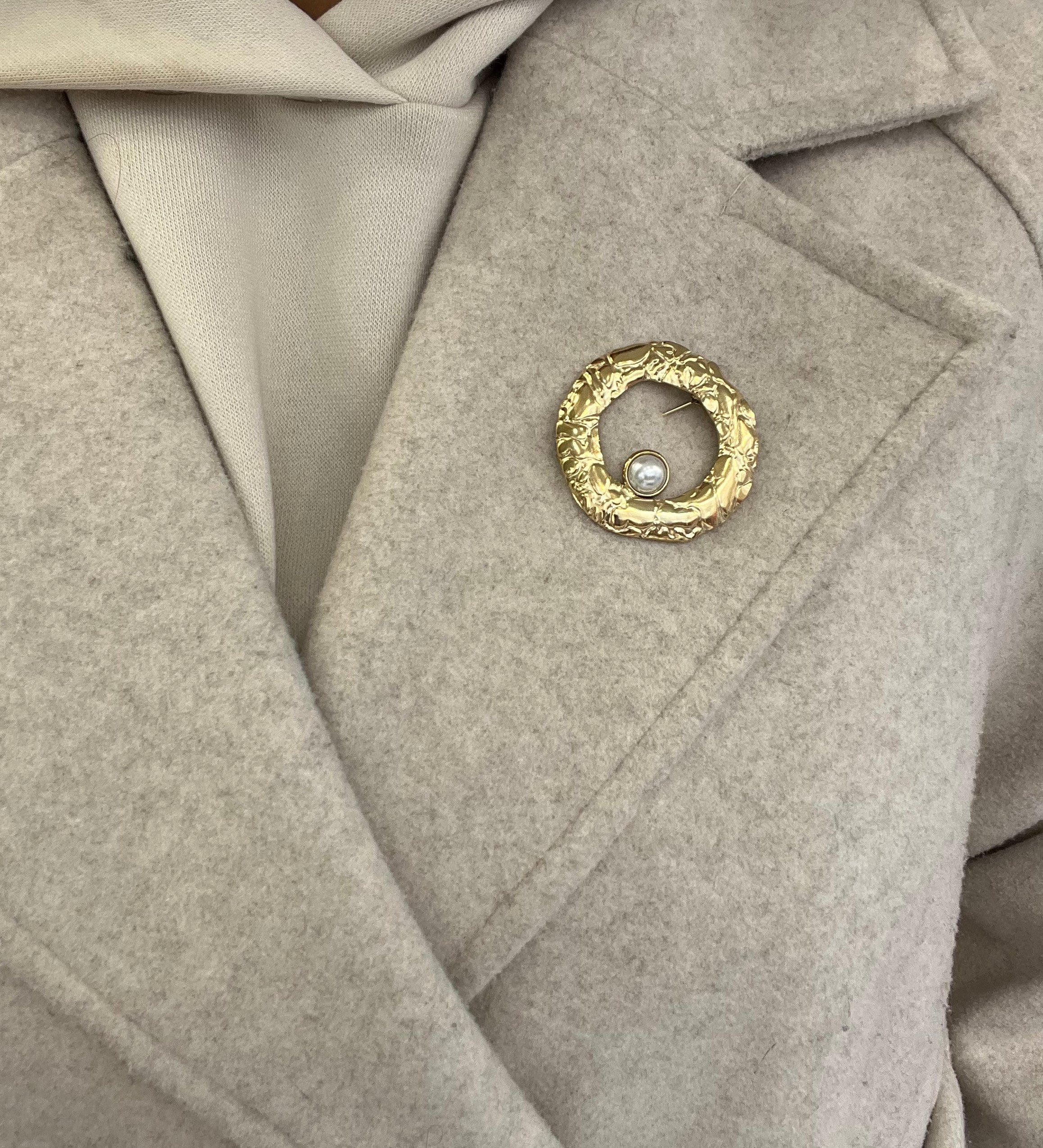 Broche Sylviane dorée en acier inoxydable anneau martelé avec perle portée sur le revers d'un manteau beige - Ordiajade
