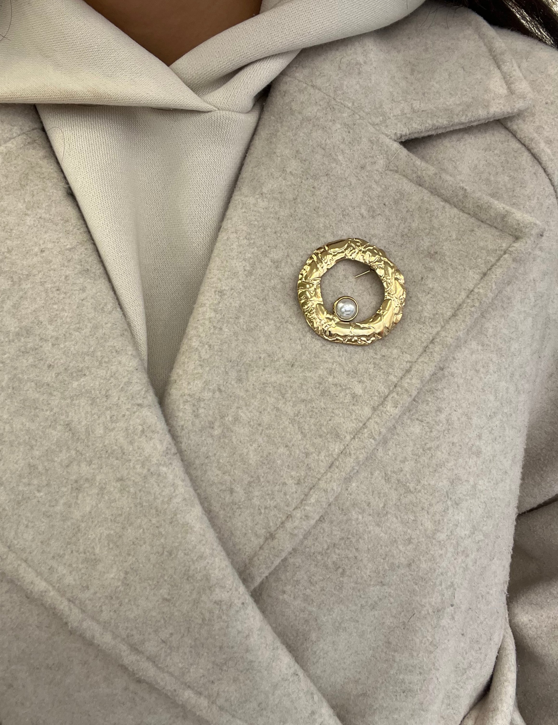Broche Sylviane dorée en acier inoxydable anneau martelé avec perle portée sur le revers d'un manteau beige - Ordiajade
