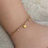 Chaîne de cheville double SHANA en acier inoxydable doré avec cœur et strass portée sur la plage - Ordiajade