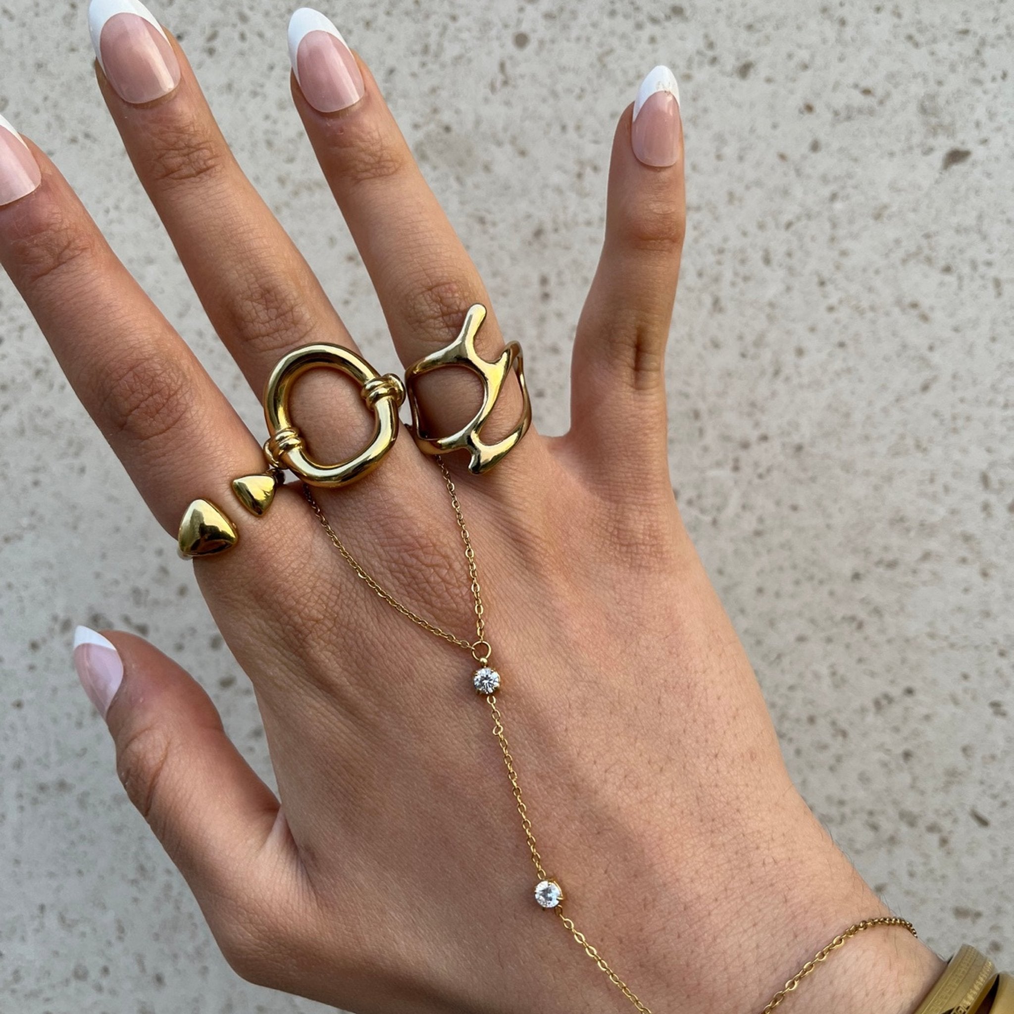 Gros plan d'un bijou de main doré et cristaux blancs porté en accumulation style luxe minimaliste.
