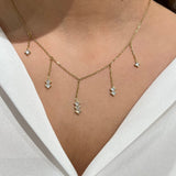Collier Fanny en acier inoxydable doré avec pampilles tombantes ornées de petits cristaux, porté sur un décolleté.
