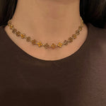 Collier Hailey Brown doré à motifs fleurs porté en ras-du-cou, style raffiné et minimaliste