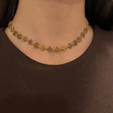 Collier Hailey Brown doré à motifs fleurs porté en ras-du-cou, style raffiné et minimaliste