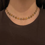 Collier doré Hailey Brown porté en ras-du-cou avec motifs fleurs