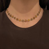 Collier doré Hailey Brown porté en ras-du-cou avec motifs fleurs