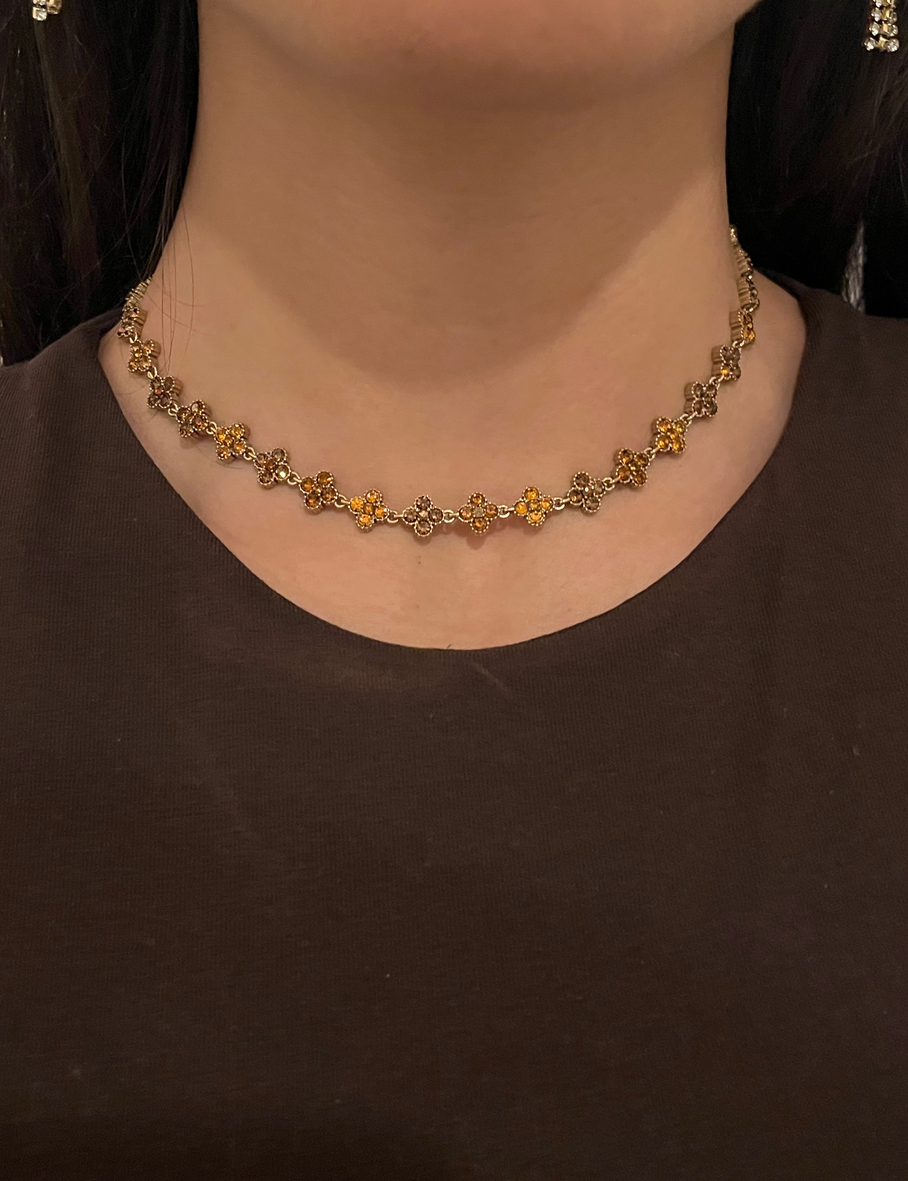 Collier doré Hailey Brown porté en ras-du-cou avec motifs fleurs