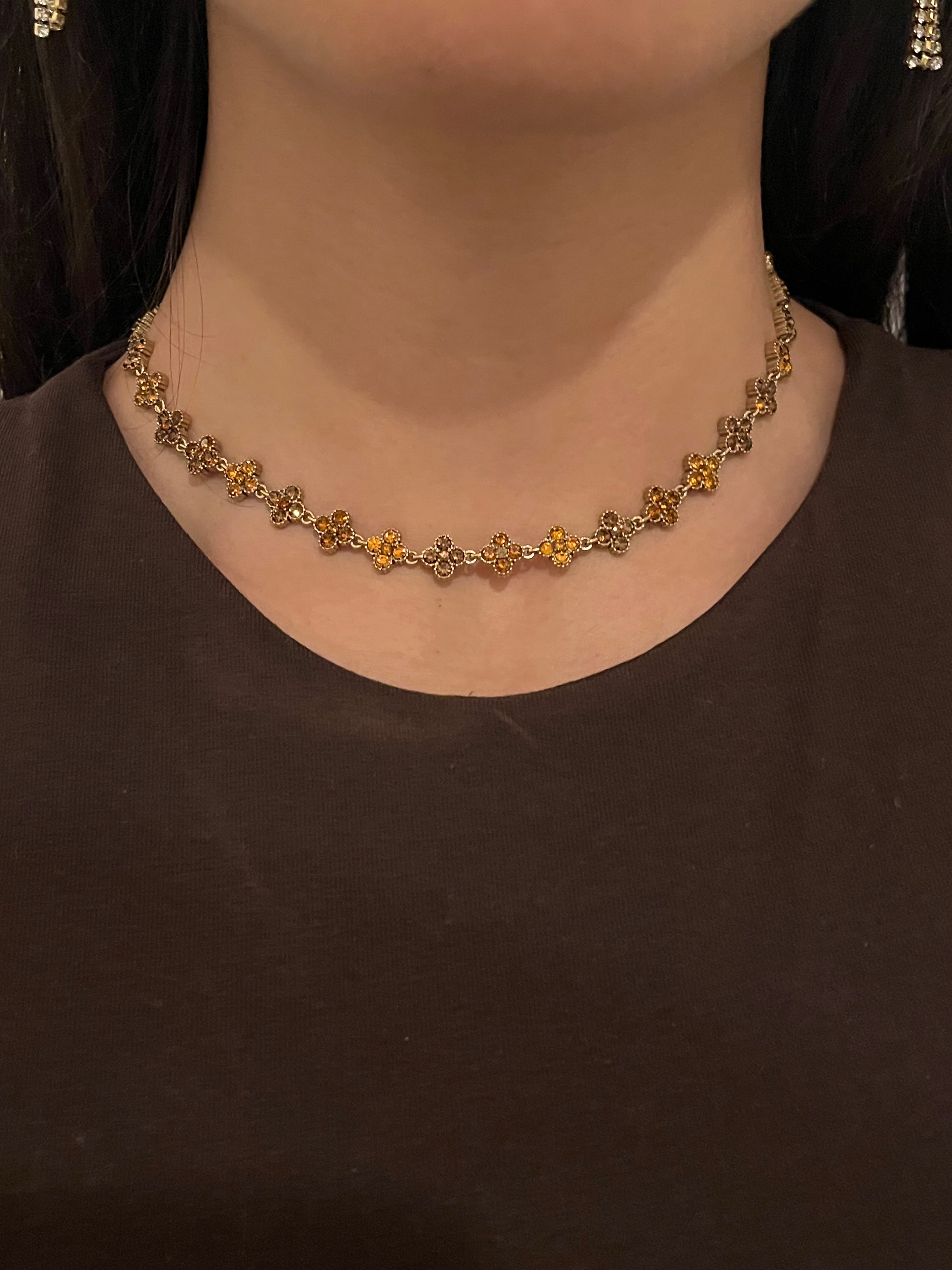 Collier doré Hailey Brown porté en ras-du-cou avec motifs fleurs