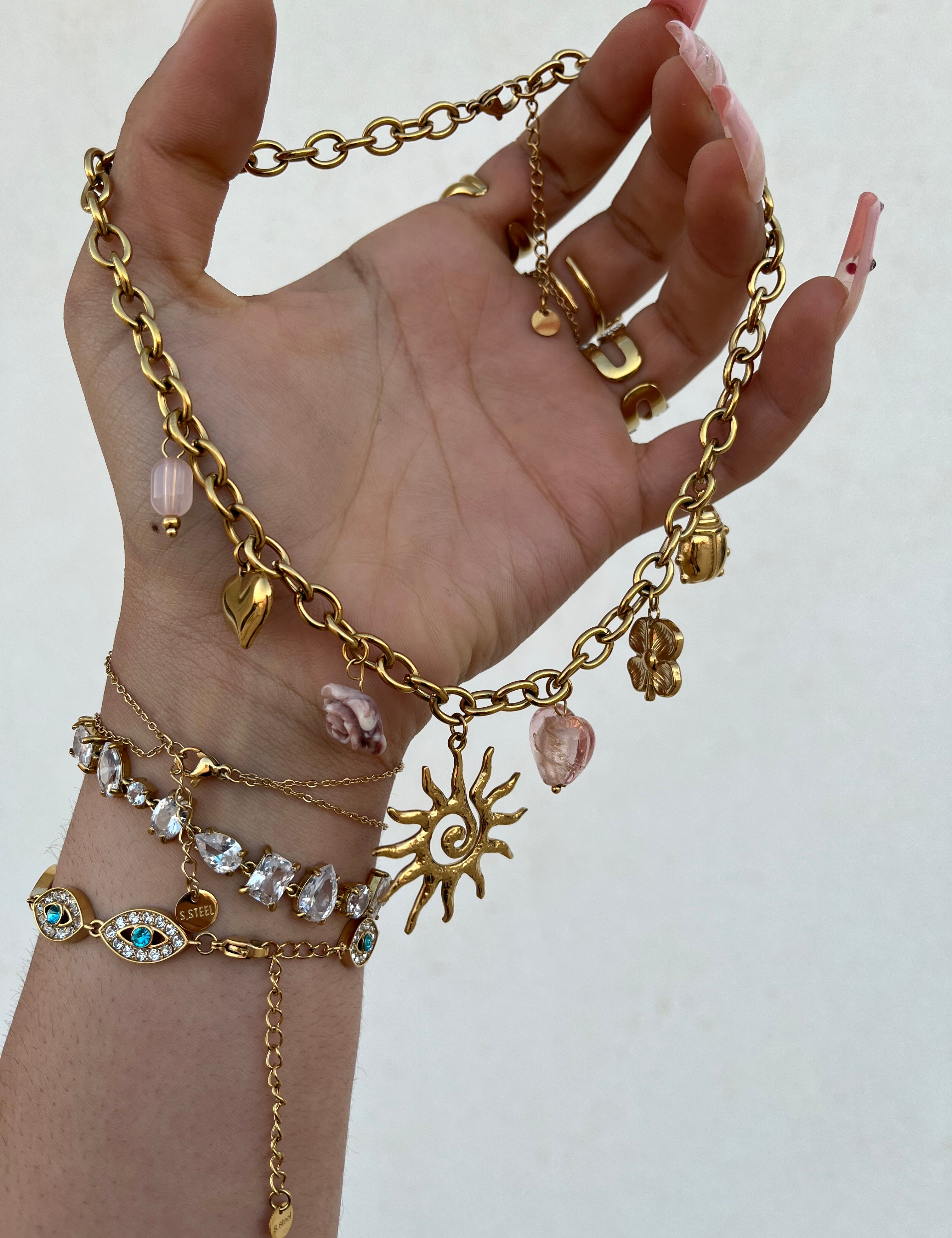 Gros plan du collier doré Haruka à pampilles et perles tenu dans la main - Ordiajade