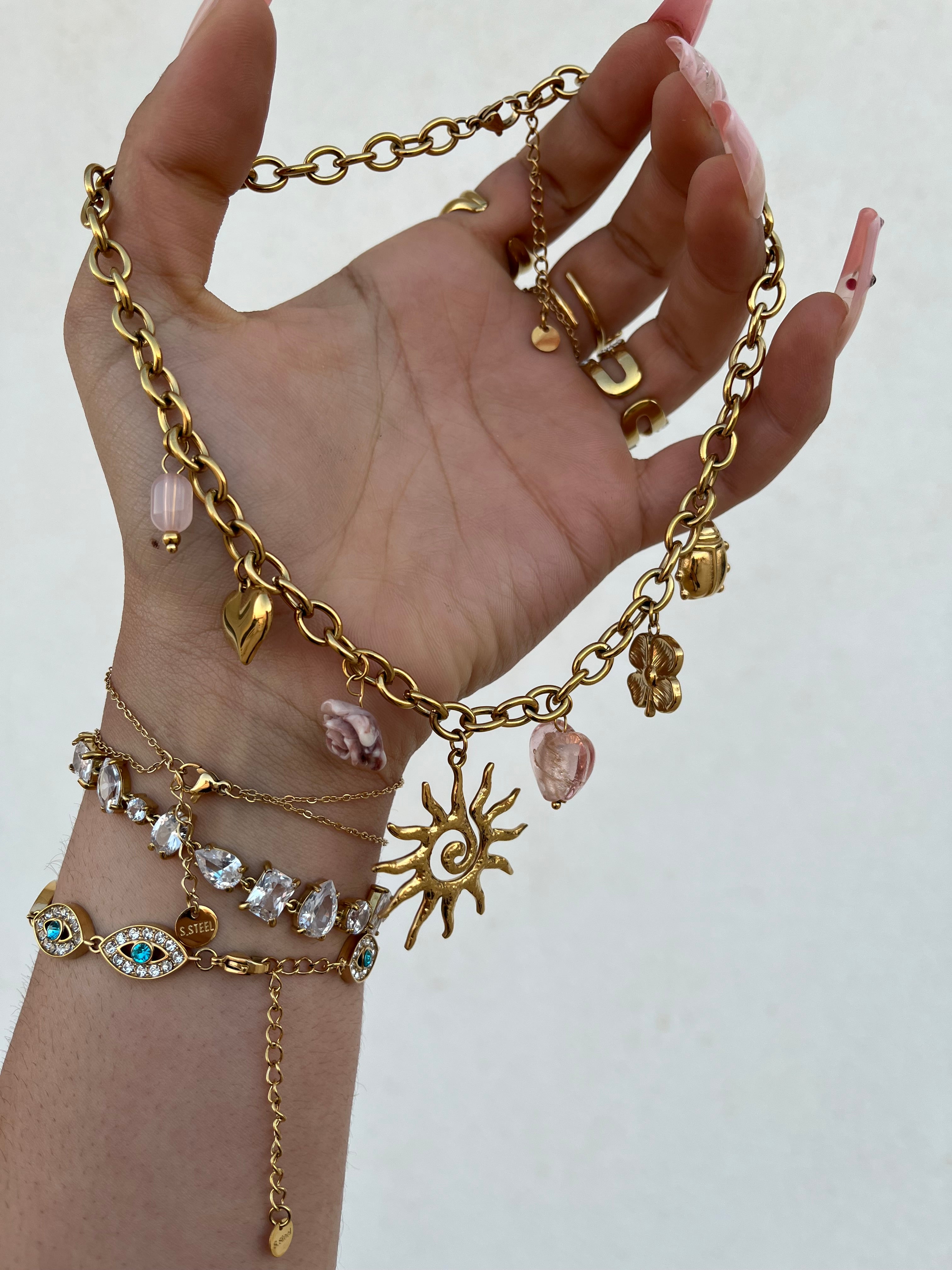 Gros plan du collier doré Haruka à pampilles et perles tenu dans la main - Ordiajade