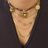 Collier Léopard porté en superposition avec d'autres colliers dorés pour un look bohème chic.
