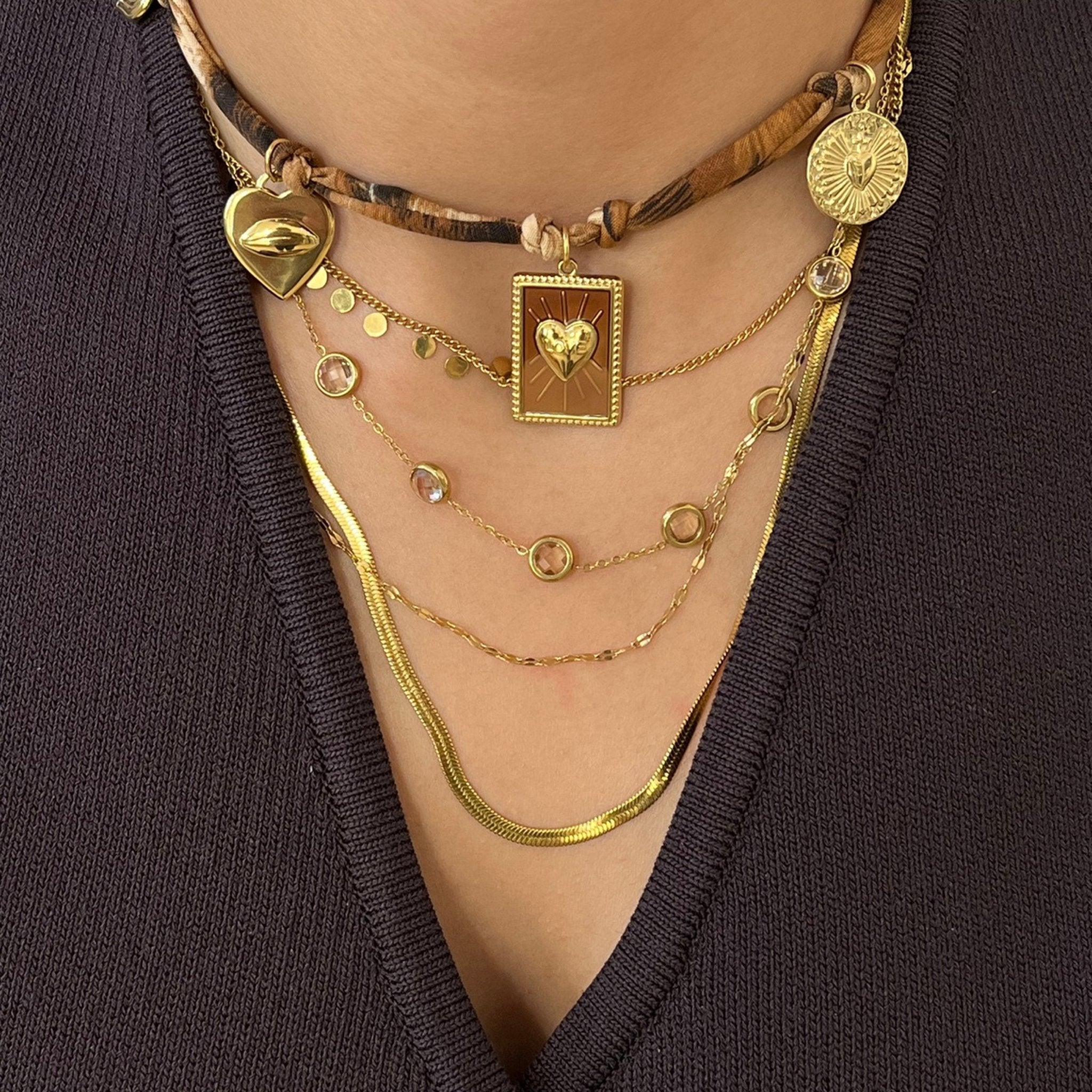 Collier Léopard porté en superposition avec d'autres colliers dorés pour un look bohème chic.