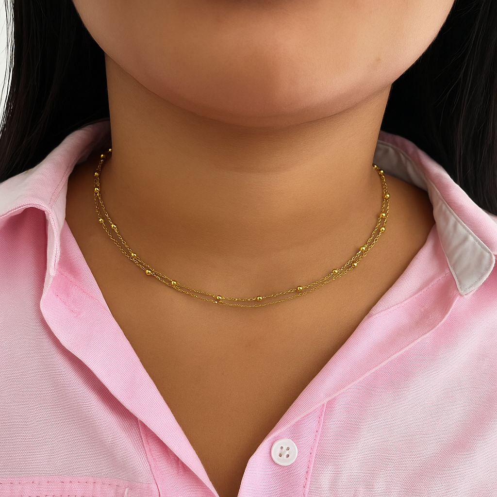 Gros plan du collier ras-de-cou double chaîne perlé doré Molly porté avec une chemise rose - Ordiajade