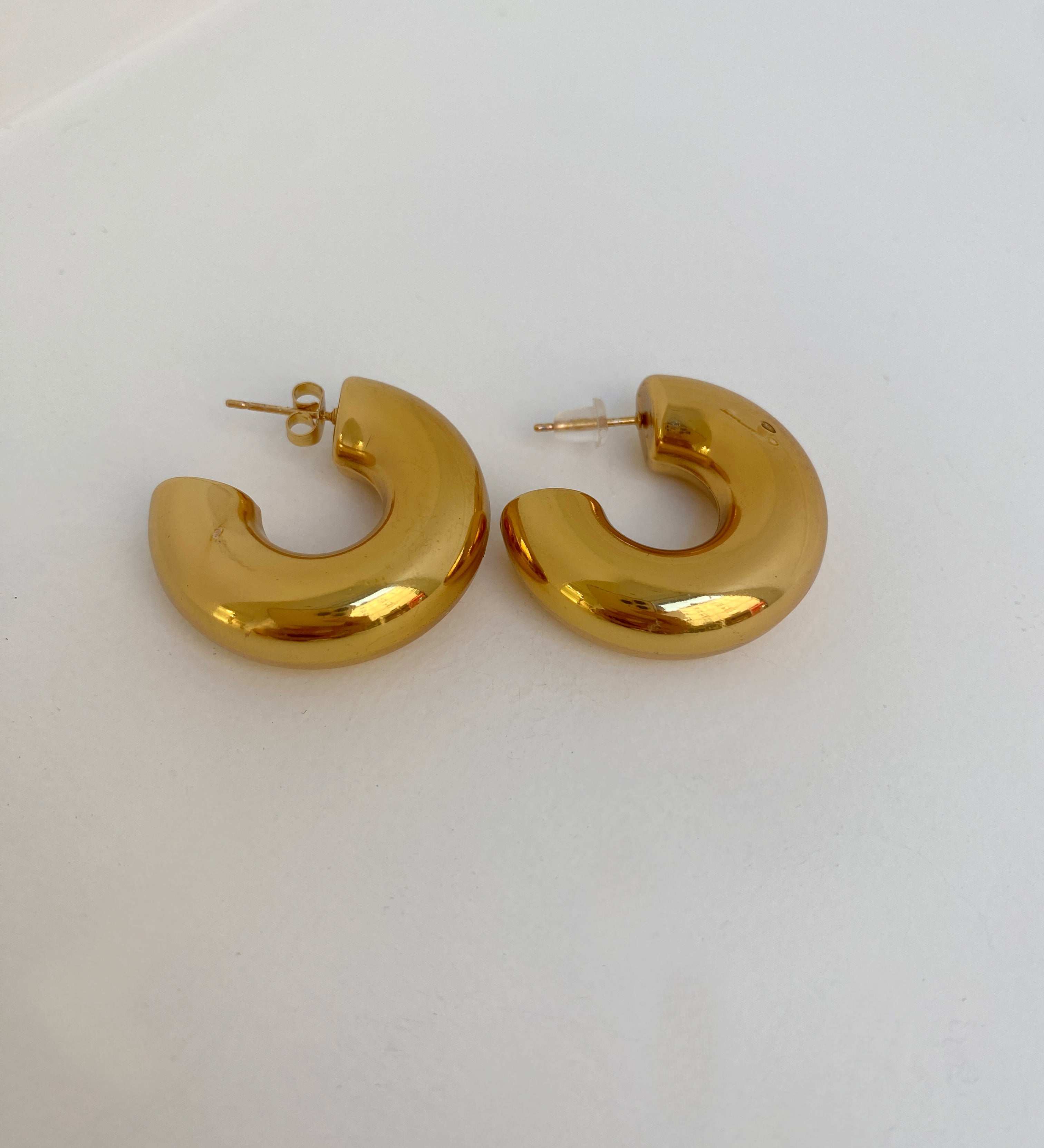 Paire de boucles d'oreilles créoles sculpturales Chéri dorées sur fond blanc - Ordiajade