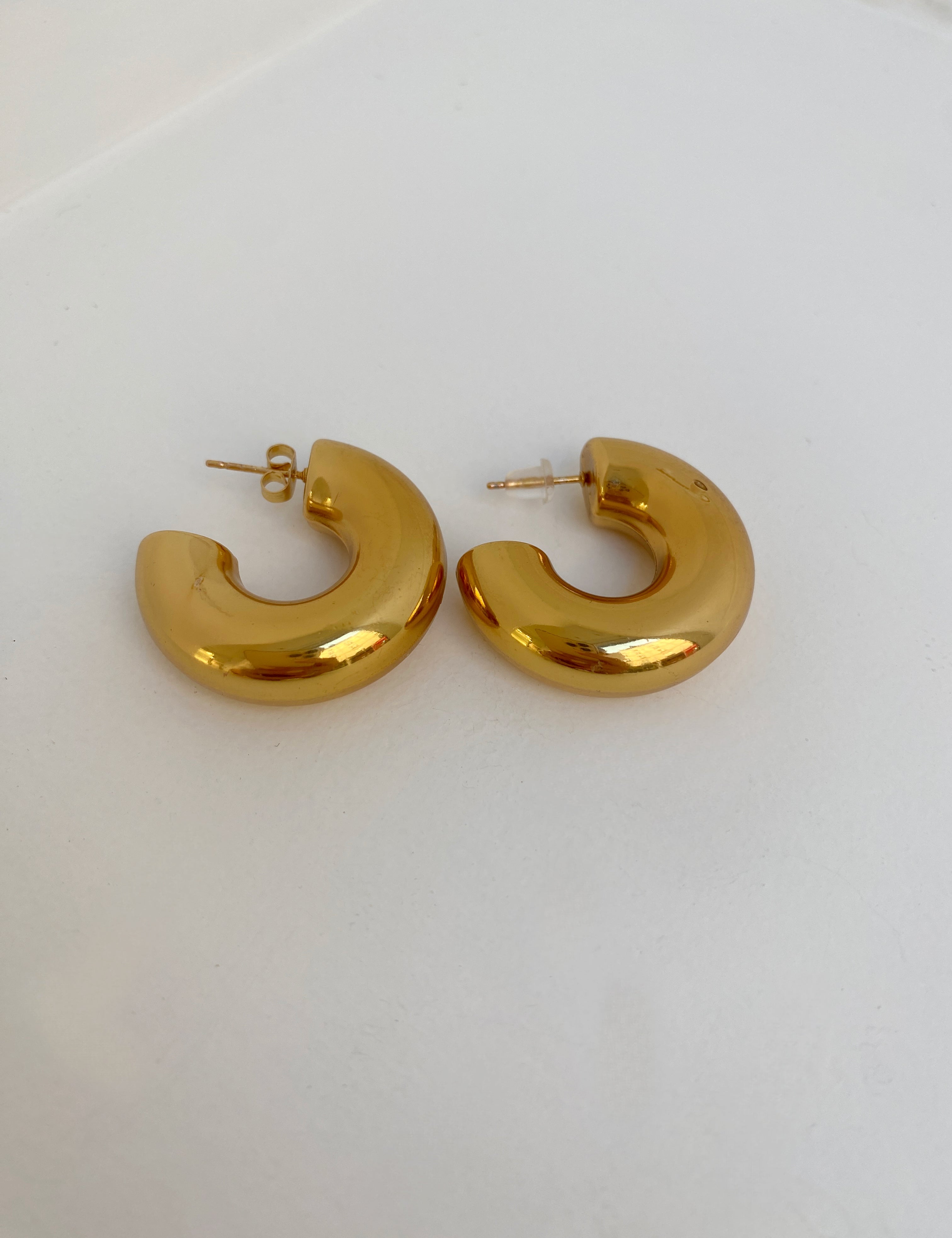Paire de boucles d'oreilles créoles sculpturales Chéri dorées sur fond blanc - Ordiajade
