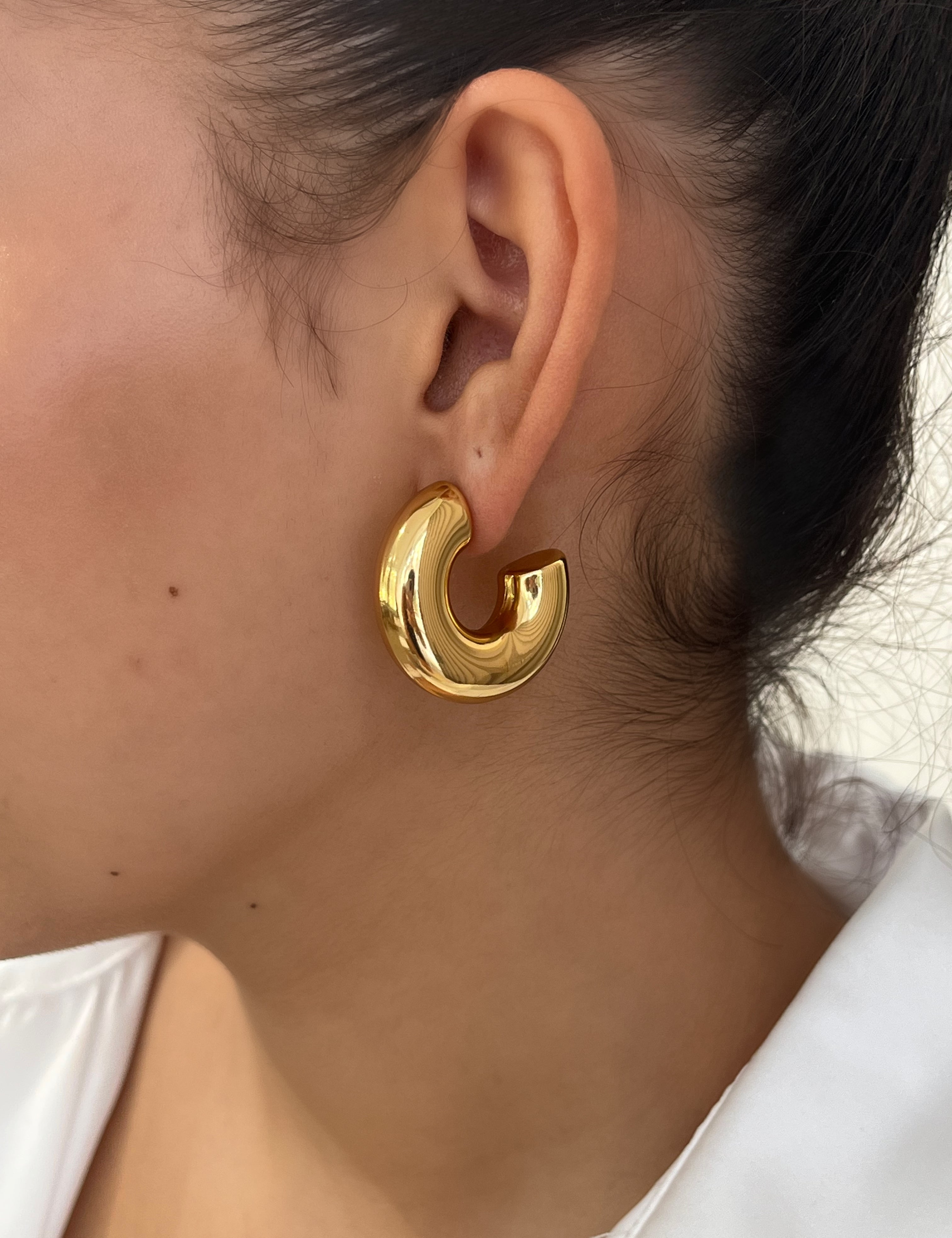 Gros plan des boucles d'oreilles créoles larges et bombées Chéri portées au lobe - Ordiajade