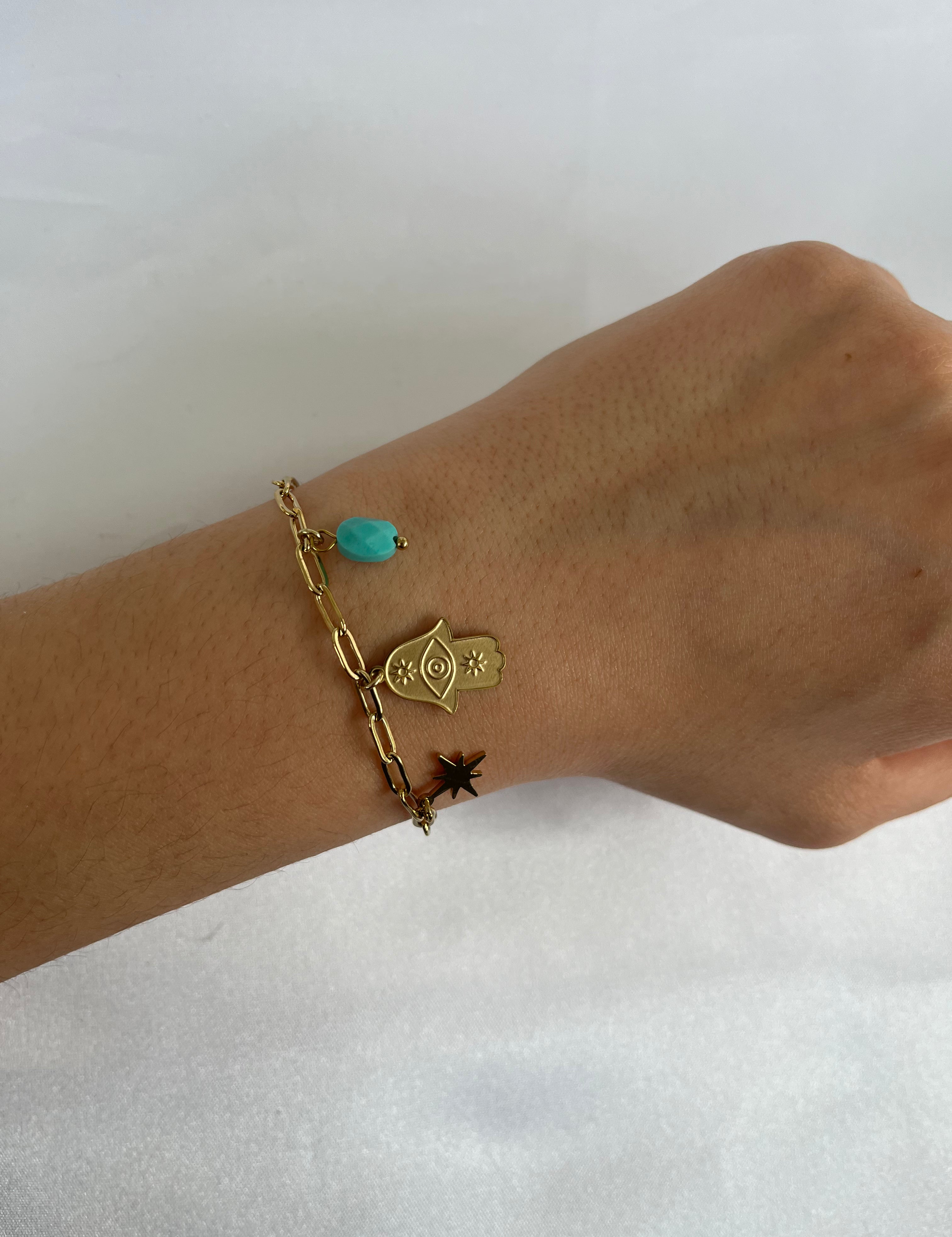 Bracelet Blue doré à breloques main de Fatma, pierre bleu-vert et étoile noire, porté au poignet - Ordiajade