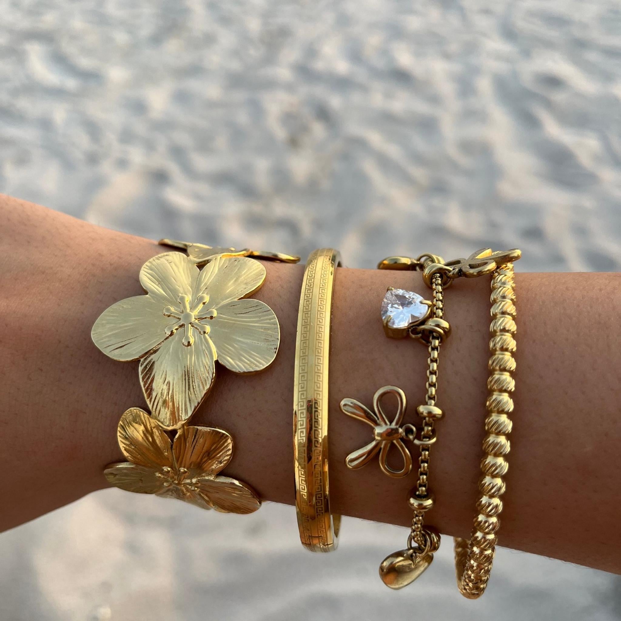 Jonc Calimara doré porté en accumulation avec d'autres bracelets au poignet - Ordiajade