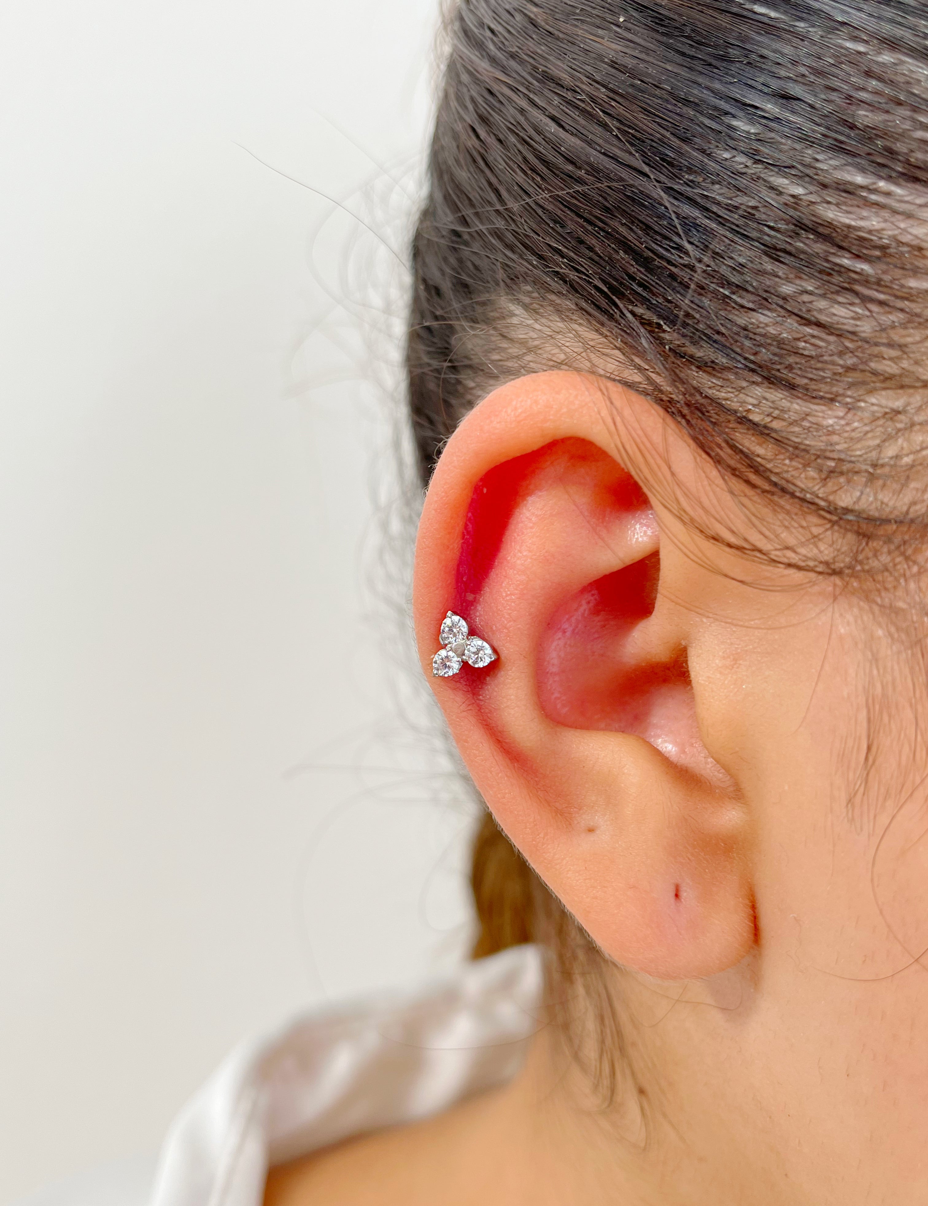 Piercing How en acier inoxydable avec trois petits cristaux, porté au cartilage de l'oreille.