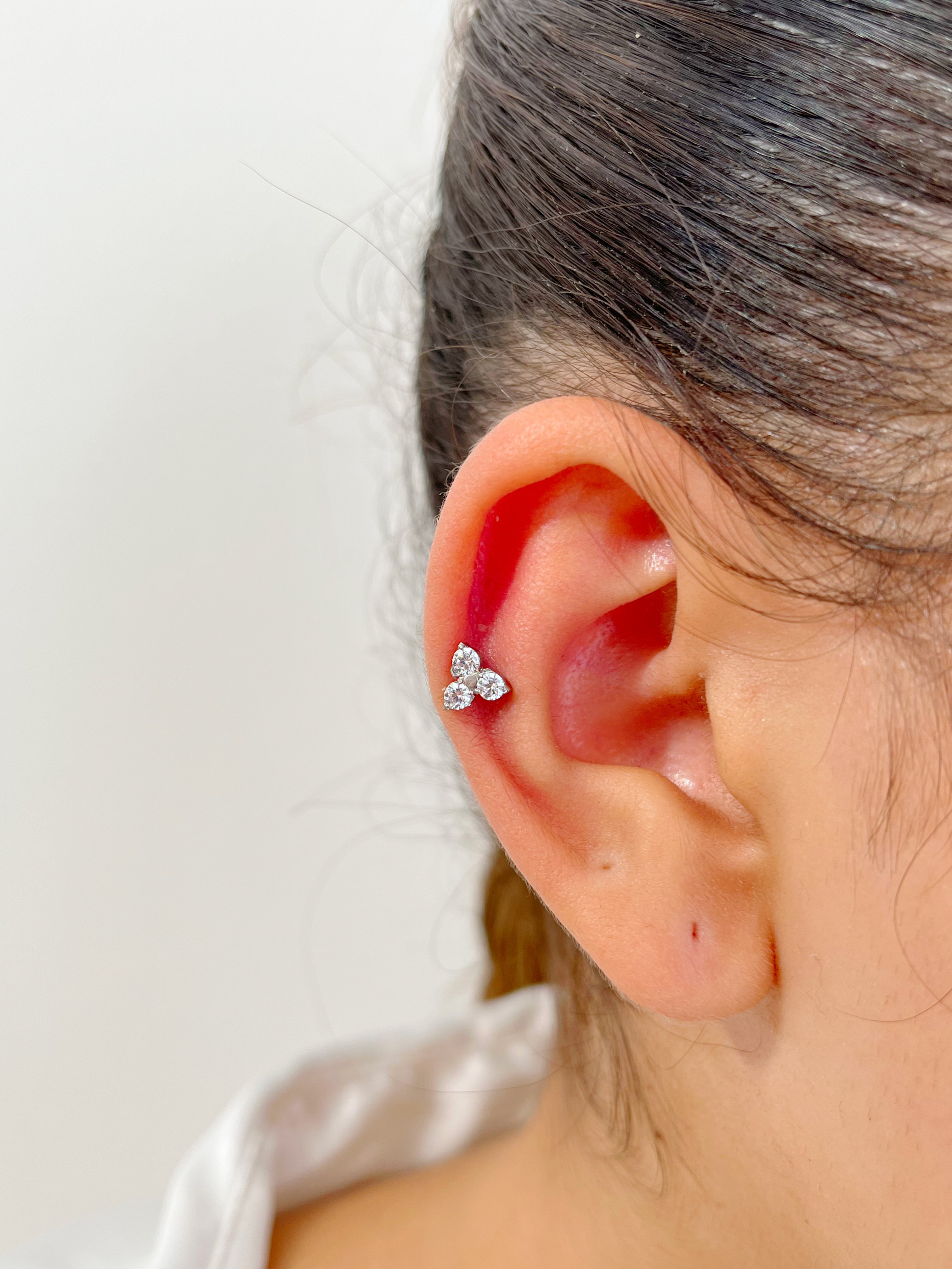Piercing How en acier inoxydable avec trois petits cristaux, porté au cartilage de l'oreille.