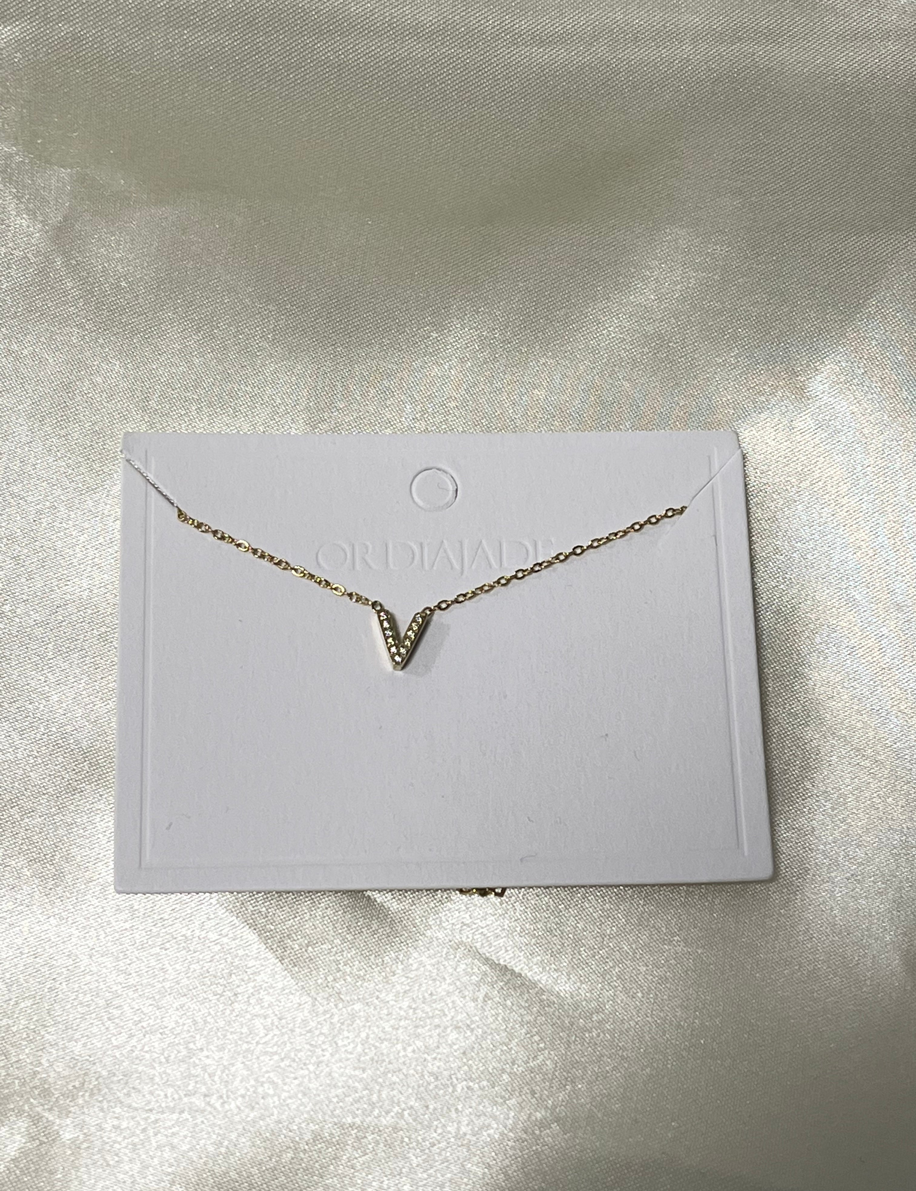 Collier Cuty doré à initiale V sertie de strass, sur sa carte de présentation - Ordiajade