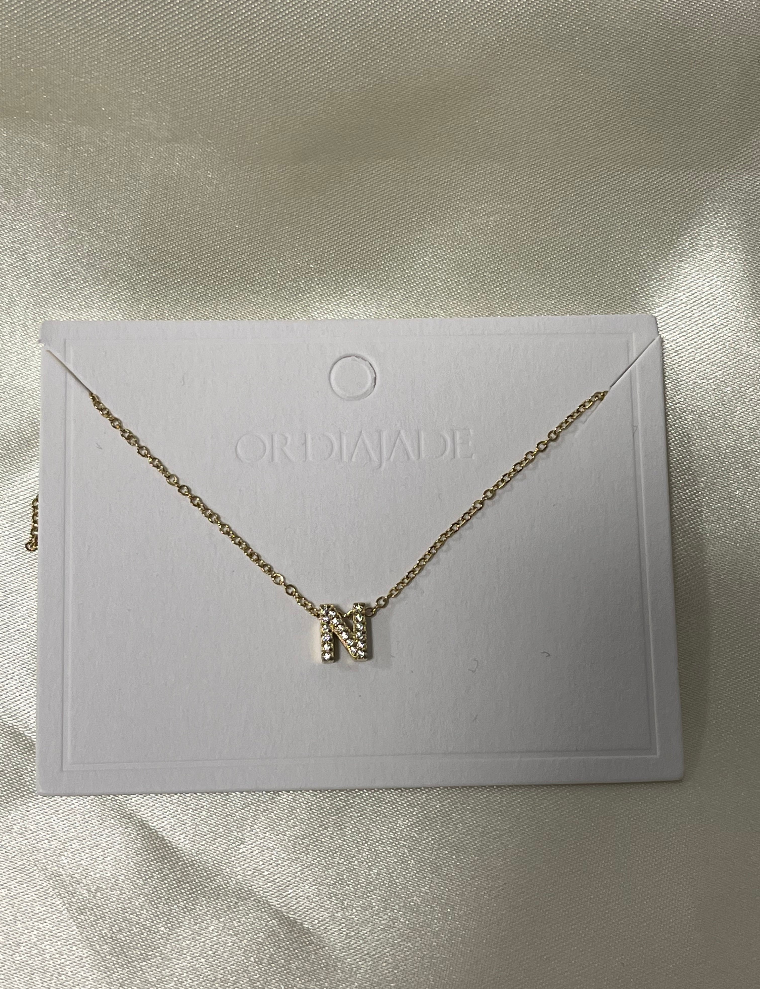 Collier Cuty doré à initiale N sertie de strass, sur sa carte de présentation - Ordiajade