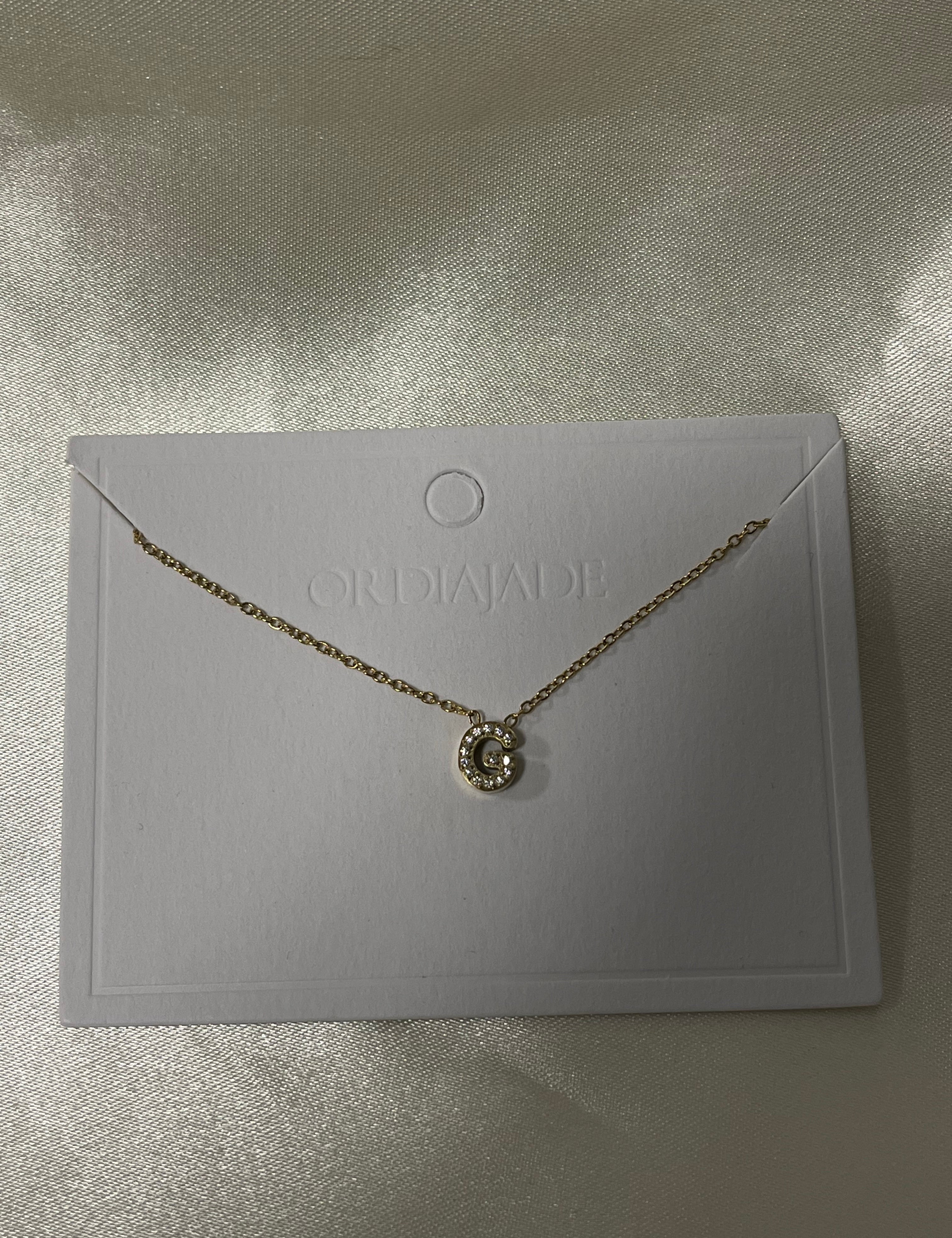 Collier Cuty doré à initiale G sertie de strass, sur sa carte de présentation - Ordiajade