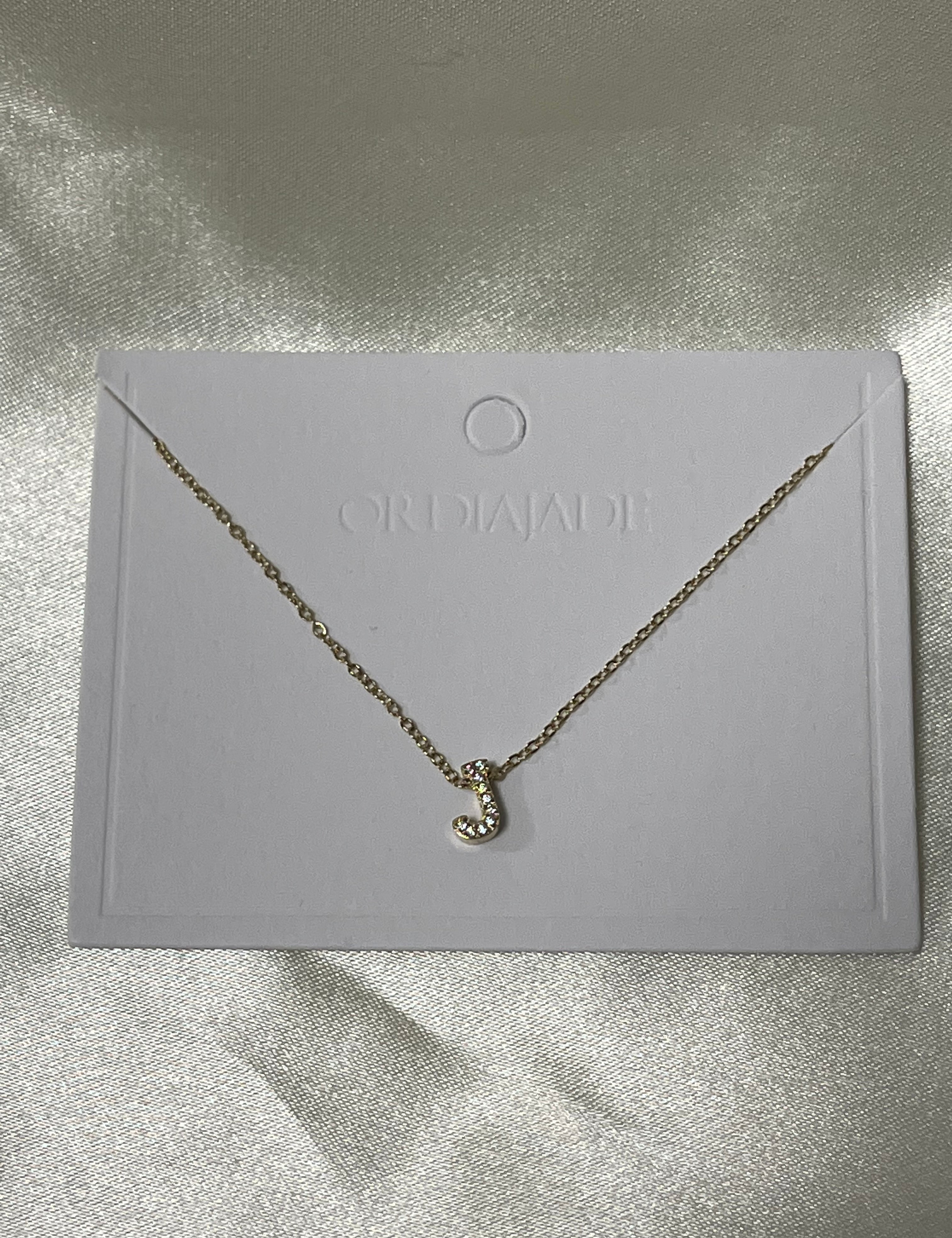 Collier Cuty doré à initiale J sertie de strass, sur sa carte de présentation - Ordiajade