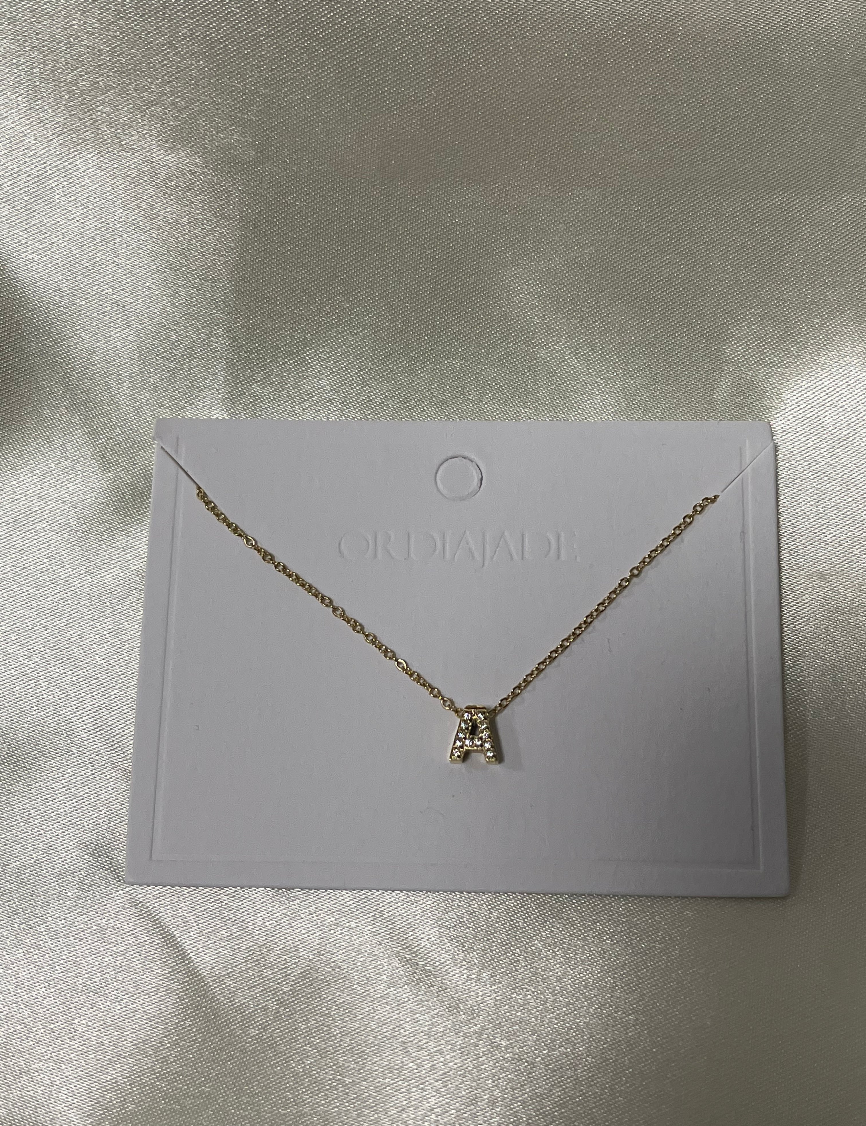 Collier Cuty doré à initiale A sertie de strass, sur sa carte de présentation - Ordiajade