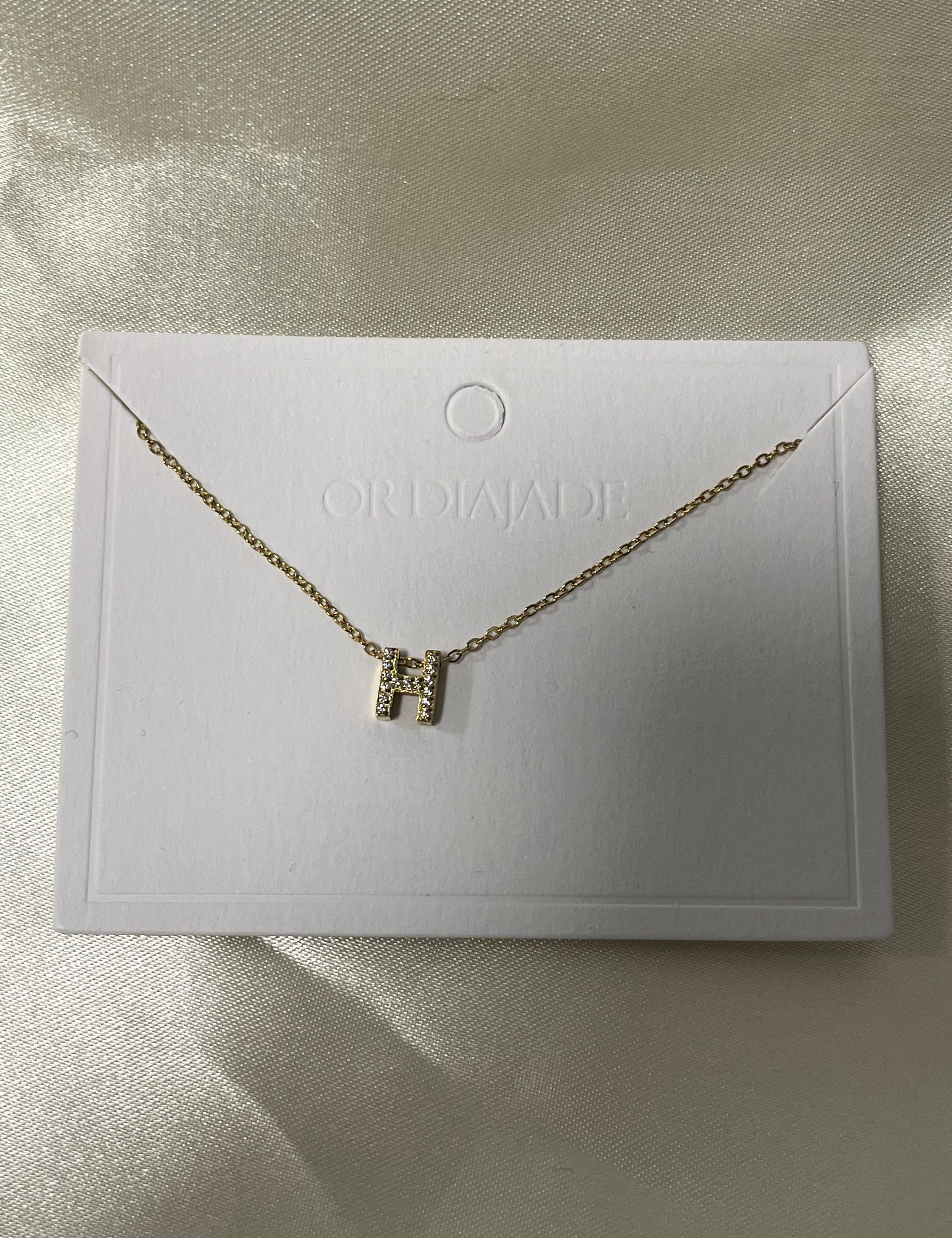 Collier Cuty doré à initiale H sertie de strass, sur sa carte de présentation - Ordiajade