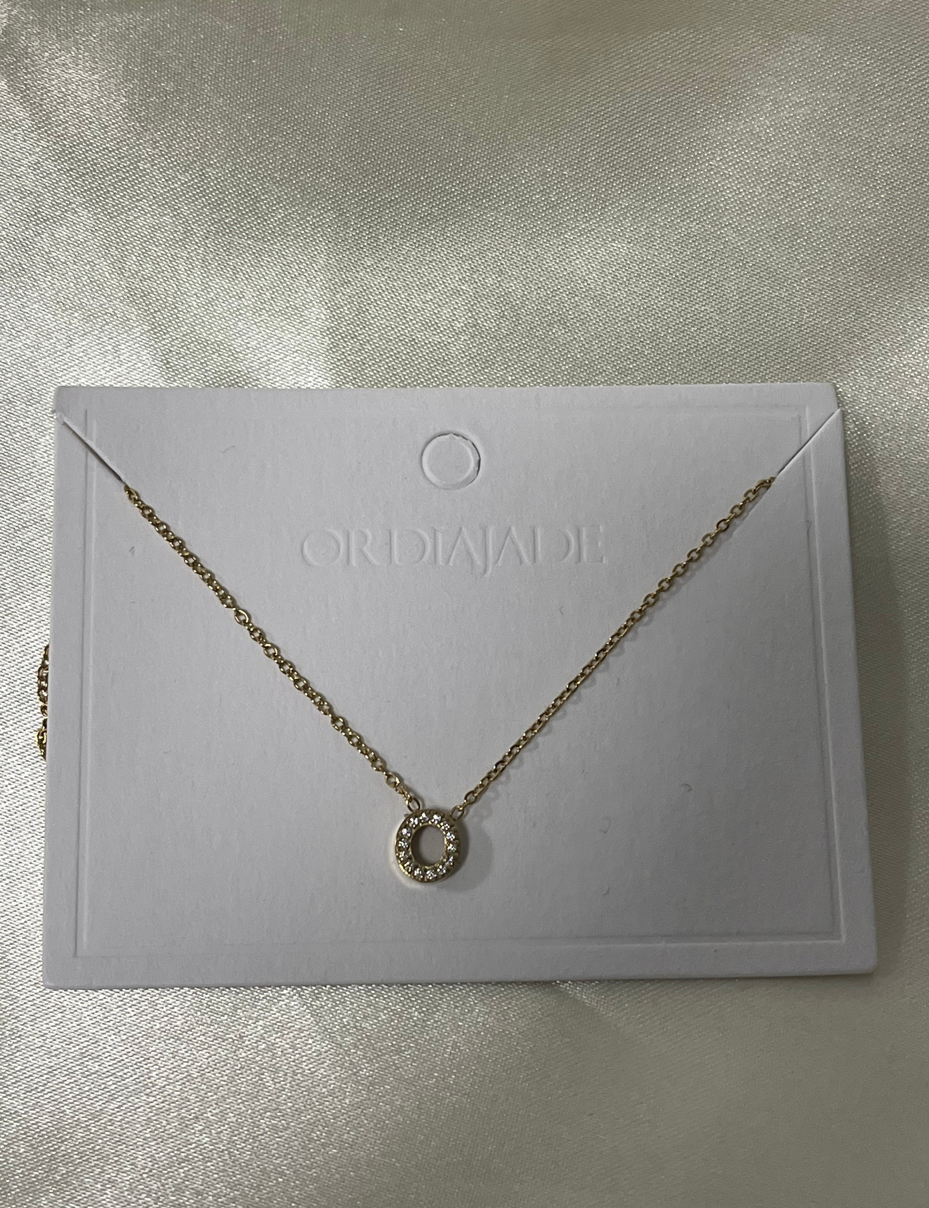 Collier Cuty doré à initiale O sertie de strass, sur sa carte de présentation - Ordiajade