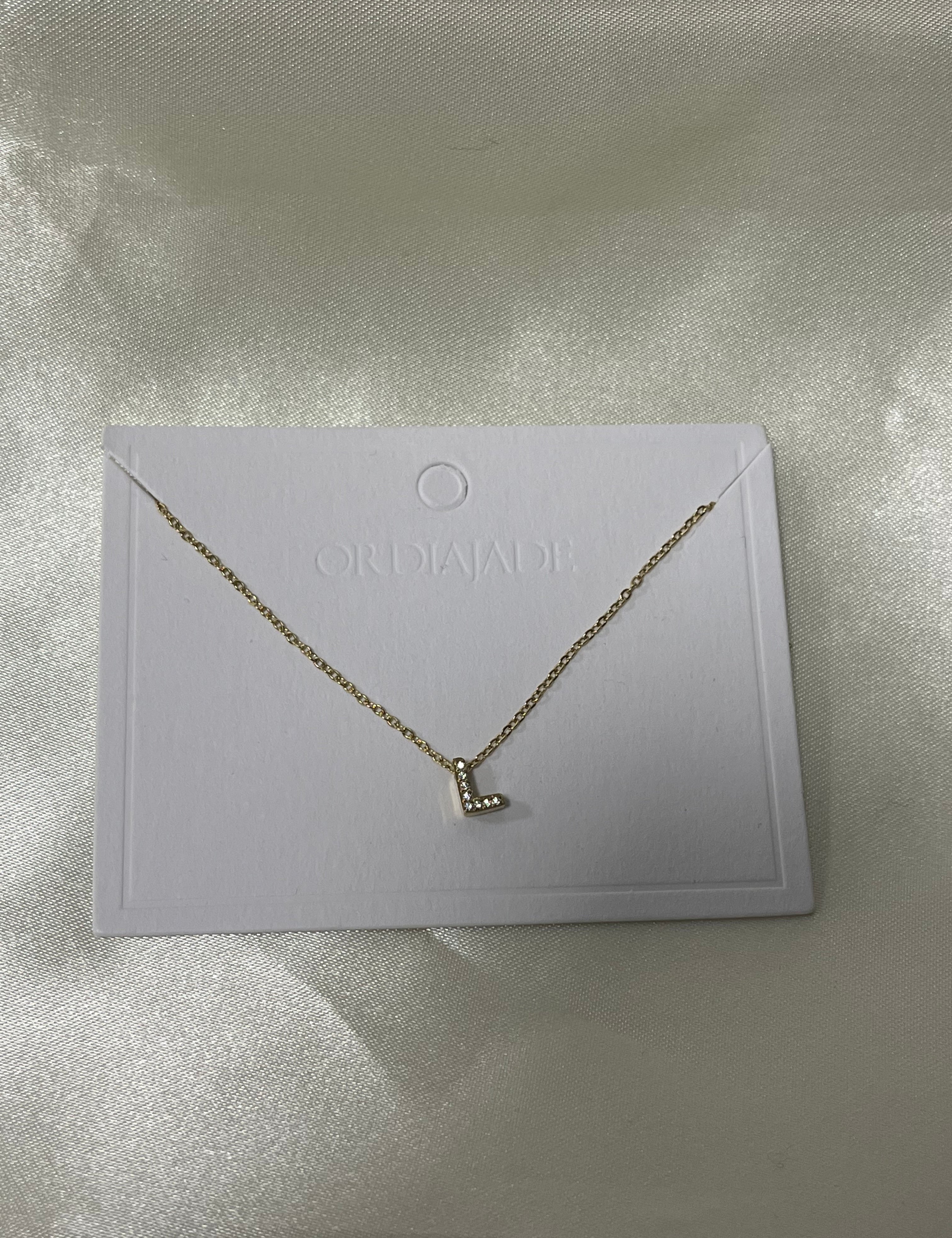 Collier Cuty doré à initiale L sertie de strass, sur sa carte de présentation - Ordiajade