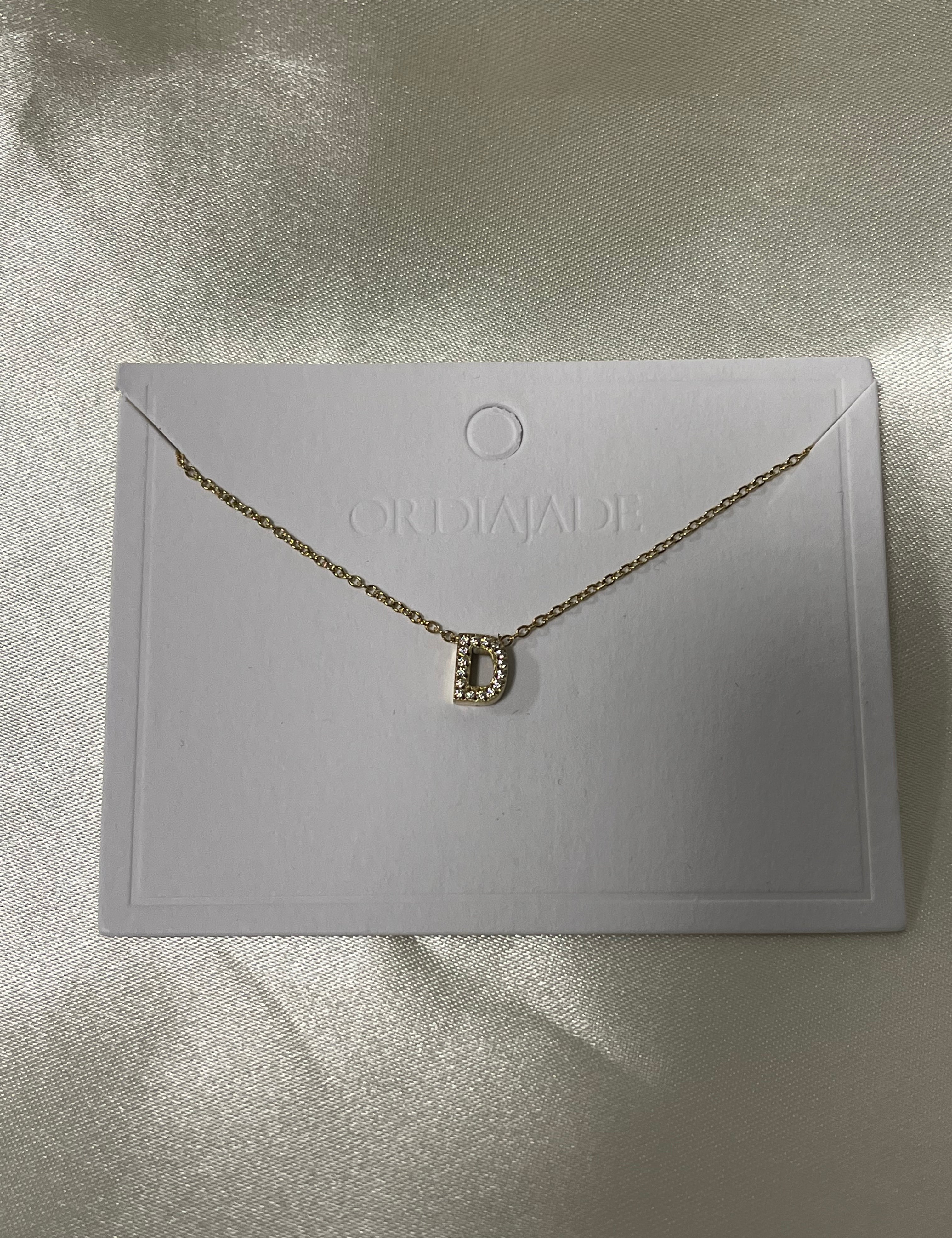 Collier Cuty doré à initiale D sertie de strass, sur sa carte de présentation - Ordiajade