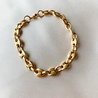 Bracelet Mouss doré à gros maillons grain de café, posé sur un tissu blanc - Ordiajade