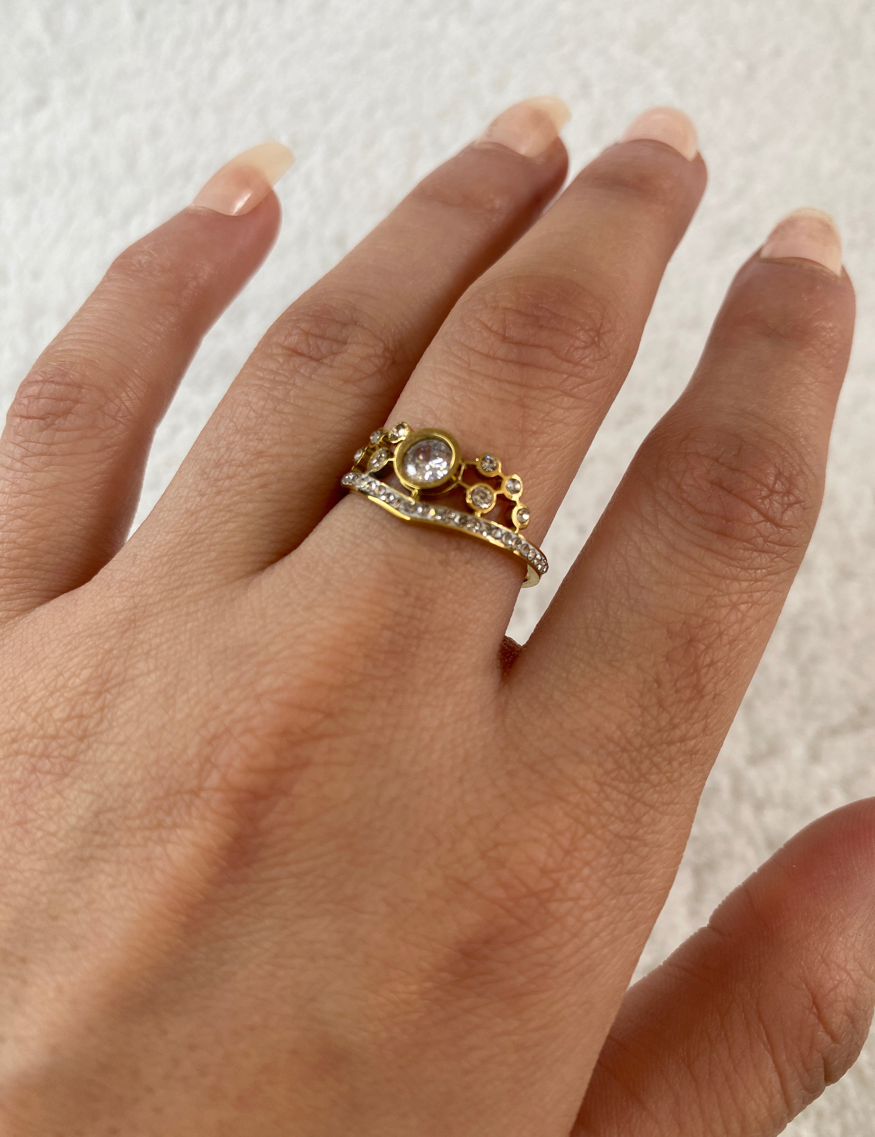 Bague Cendrillon dorée sertie d'une pierre ronde entourée de strass, portée au doigt - Ordiajade